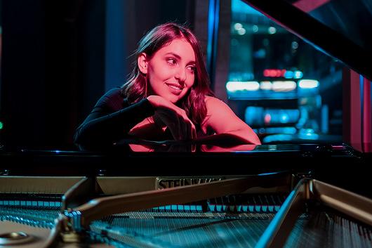 Person sitting at an open piano with red light shining